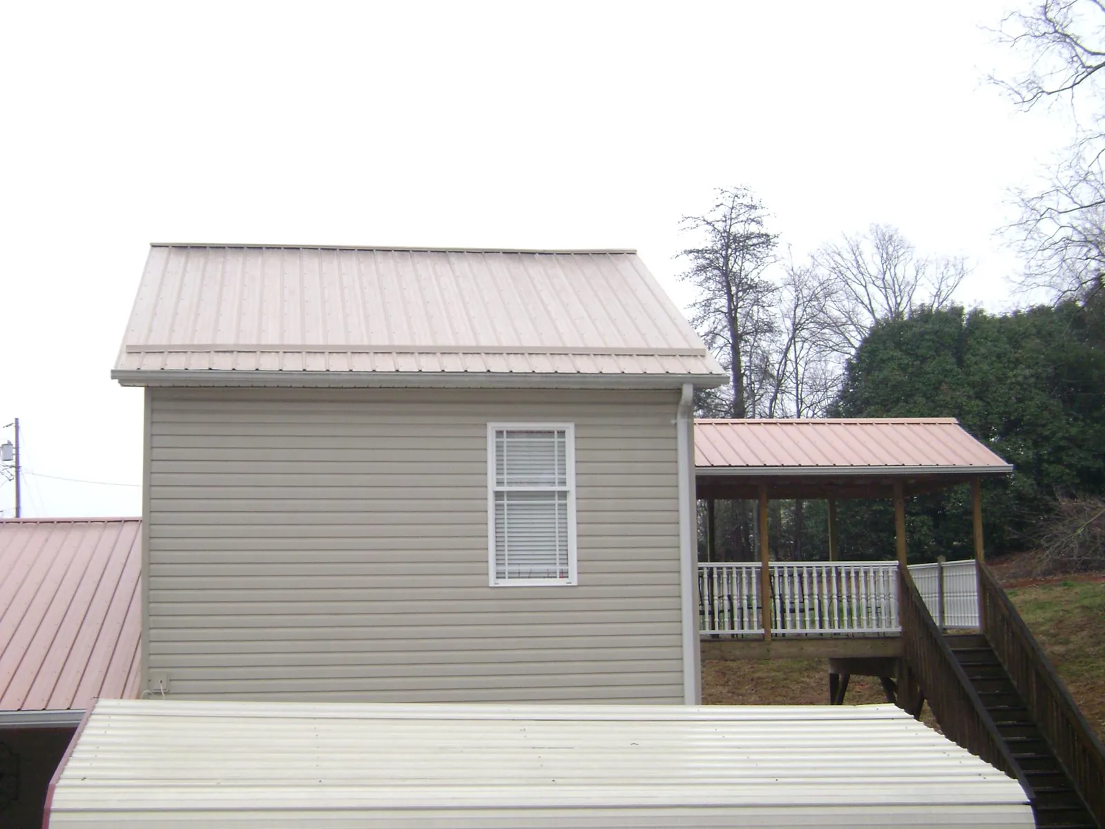 Tan metal roofs on a two story addition and attached porch, from a Roof Replacement job in Townsend