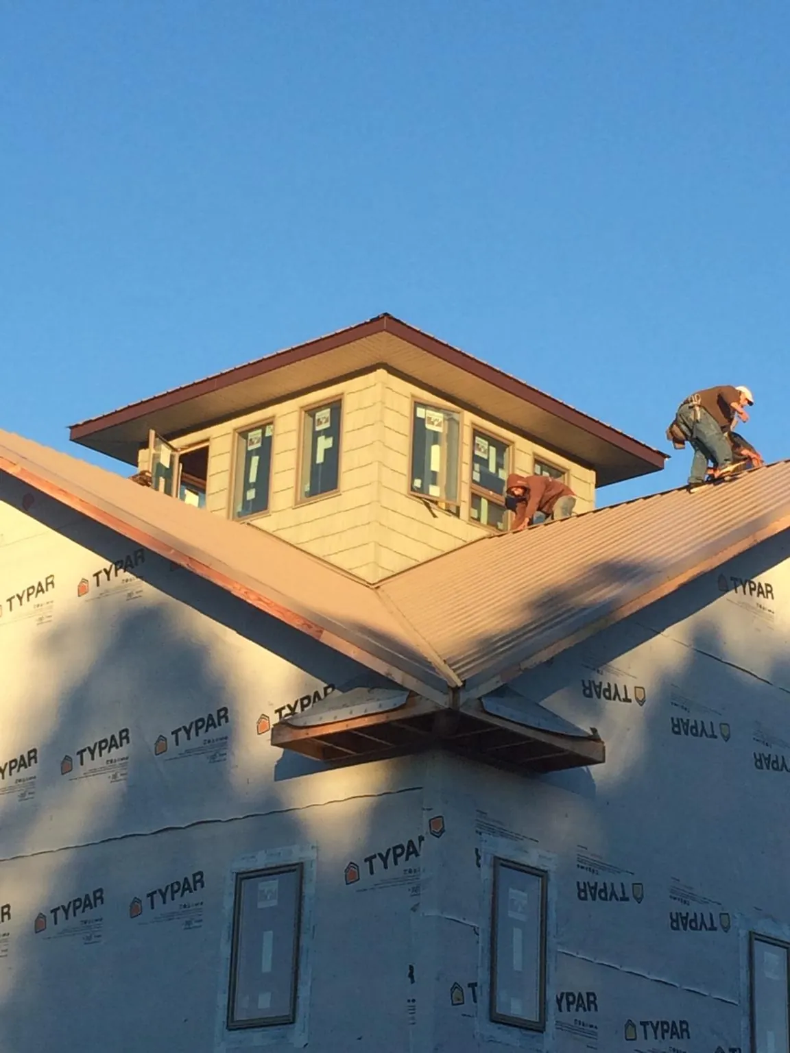 Roofers working around a rooftop cupola on a new metal roof at sunset — Roof Waterproofing in Townsend by Roofing Brothers